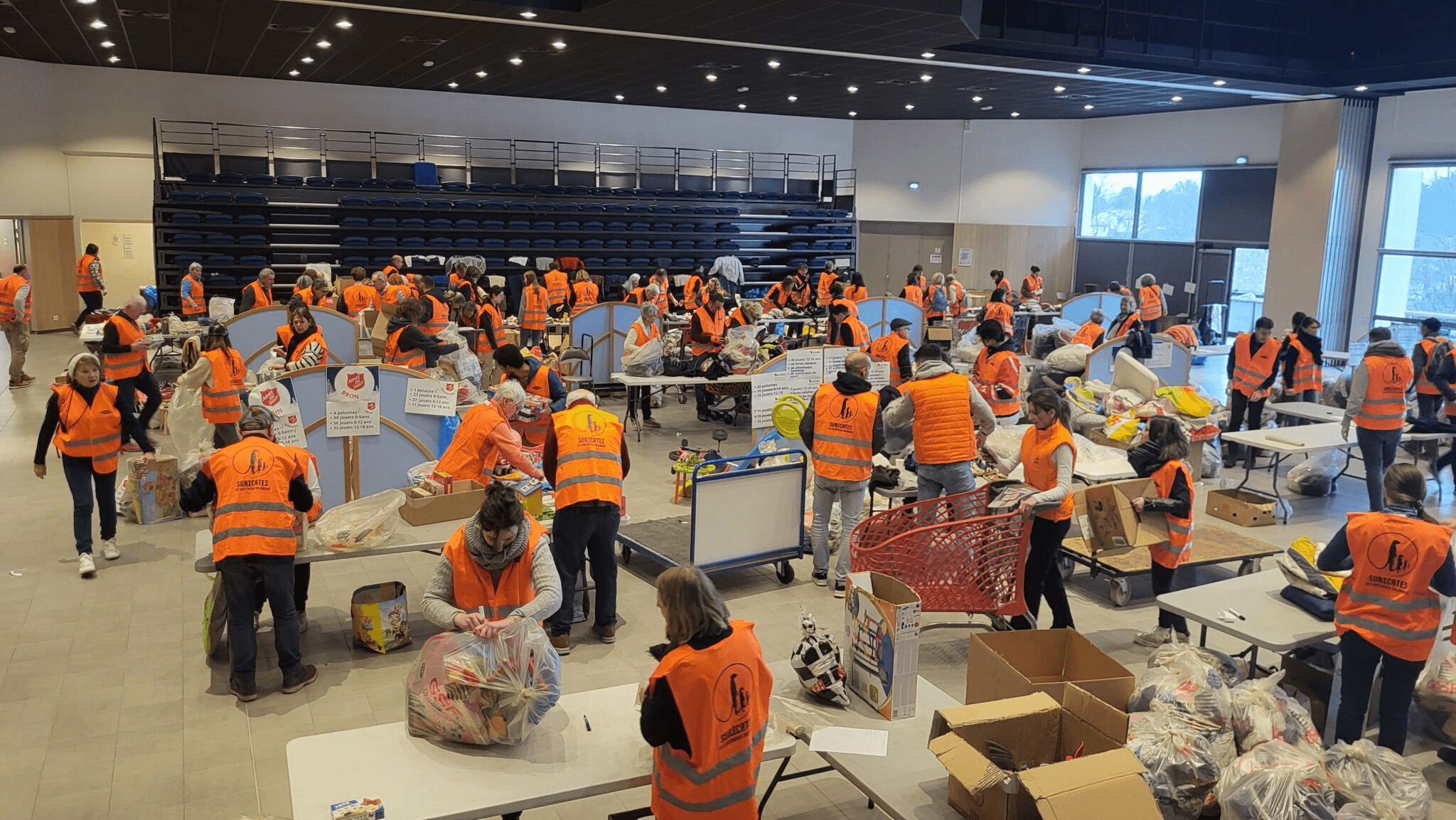 Bénévoles en gilet orange préparant les dons de Noël Solidaire